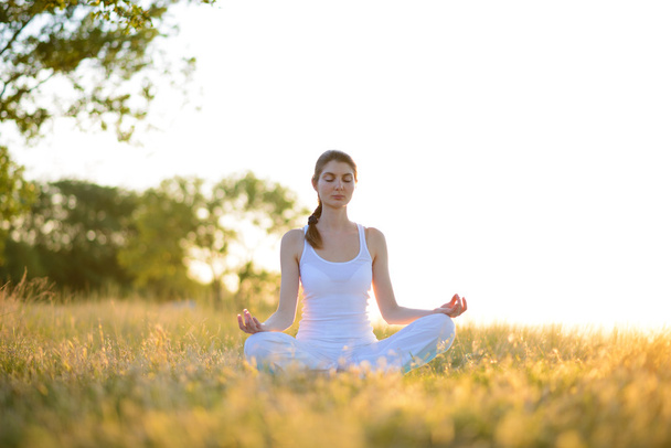 Joven hermosa mujer practica yoga en el prado soleado
 - Foto, imagen