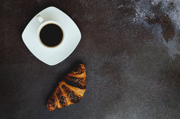 Geschäftsmann, der morgens mit Notizbuch, heißem Kaffee und süßem Croissant auf schwarzem Hintergrund arbeitet. Draufsicht, Kopierraum, Attrappe. Flach lag er. Moderne Frühstücksspeisen. - Foto, Bild