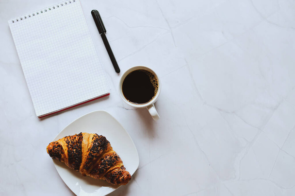 Businessman working morning with notebook, pen, cup of hot coffee and croissant on white background. Top view, copy space, mockup. Flat lay. Healthy food concept. - Photo, image