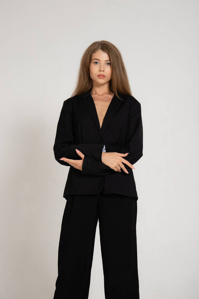 Girl in a black jacket and trousers on a white background - Φωτογραφία, εικόνα