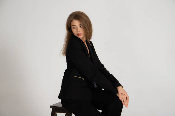 Girl in a black jacket and trousers on a white background - Foto, imagen