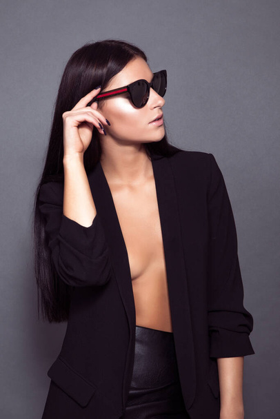 beautiful young woman in black sunglasses and glasses on a gray background - Foto, Imagen