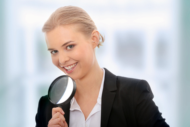 Business woman looking into a magnifying glass - Zdjęcie, obraz