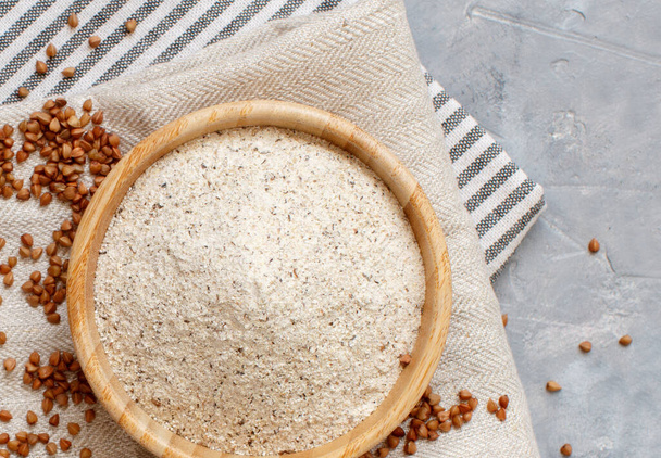 Buckwheat flour in a bowl and buckwheat grain top view - Foto, Imagen