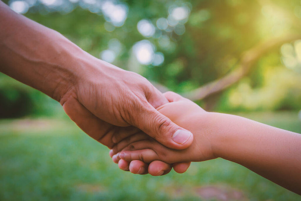 Adult and child shaking hands isolated on a green background - Photo, Image