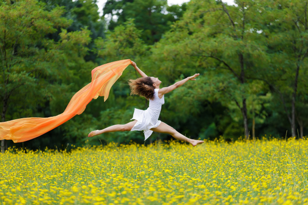 Mulher ágil pulando no ar seguindo um lenço
 - Foto, Imagem
