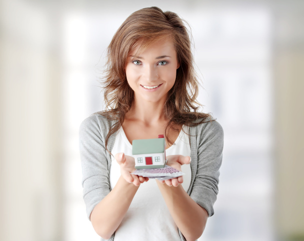 Woman holding euros bills and house model - Foto, afbeelding
