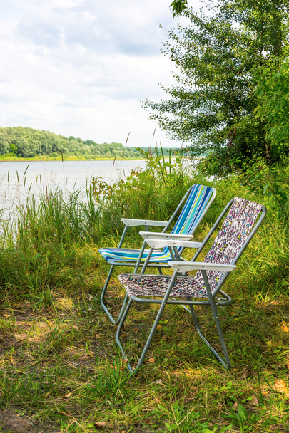 Deux chaises pliantes sur la nature, sur les rives de la rivière
 - Photo, image