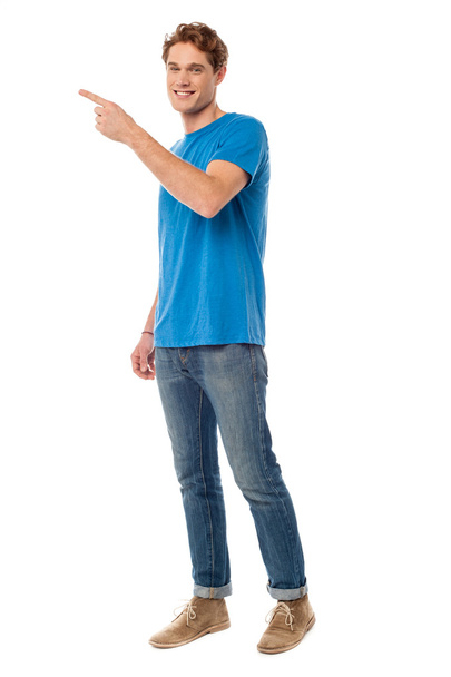 Smiling young man pointing to the side - Foto, Bild