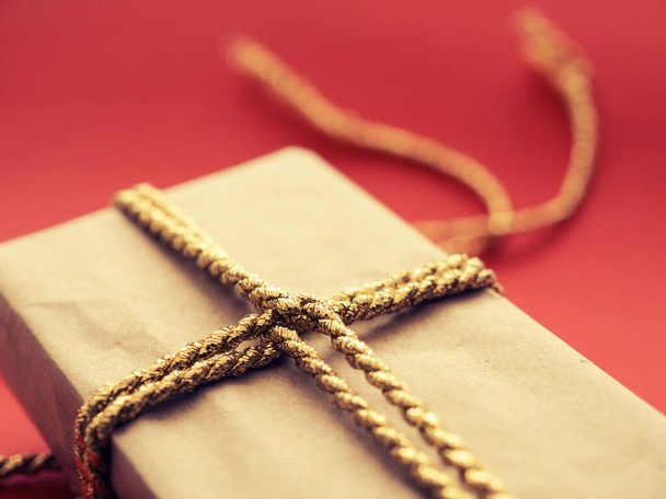 A Christmas present with golden gift bank on a red background, selective focus on the foreground - 写真・画像