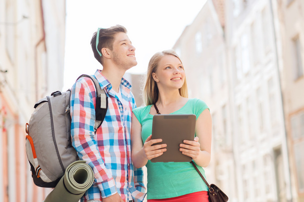 smiling couple with tablet pc and backpack in city - Foto, Imagen