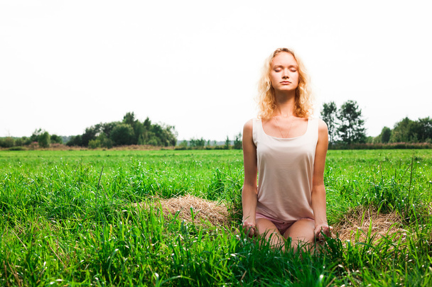 Beautiful woman meditating in summer park - Фото, изображение