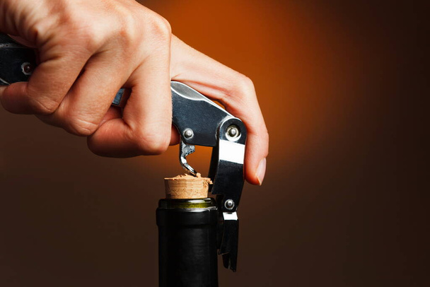 hand holding a corkscrew on a black background - Zdjęcie, obraz