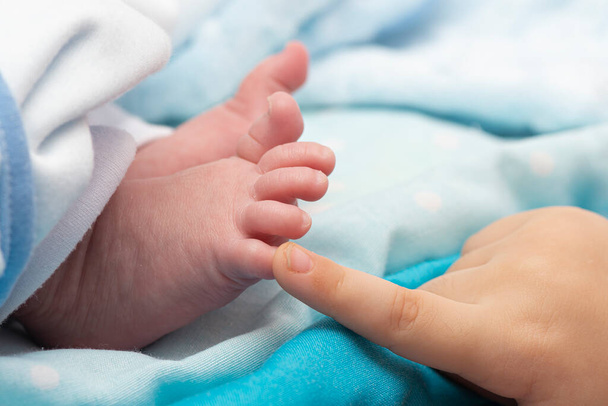 A little girl touching newborn baby foot at bed- close-up macro shot - Foto, immagini