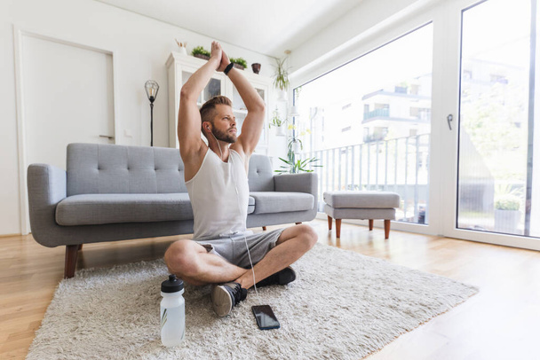 Handsome young man working out at home in the living room - Φωτογραφία, εικόνα