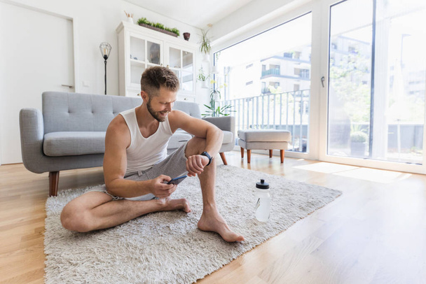 Handsome young man working out at home in the living room - 写真・画像