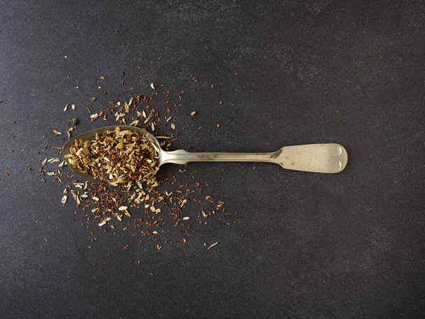 Organic tea blend on a rustic spoon, dark stone background with space for text - Zdjęcie, obraz