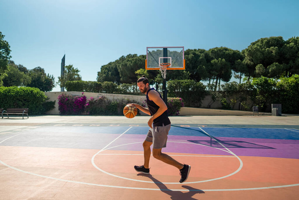 Ο μπασκετμπολίστας προπονείται σε γήπεδο μπάσκετ με μπάλα. - Φωτογραφία, εικόνα