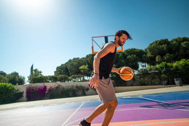 basketball player trains himself on a basketball court with a ball - Foto, Imagen