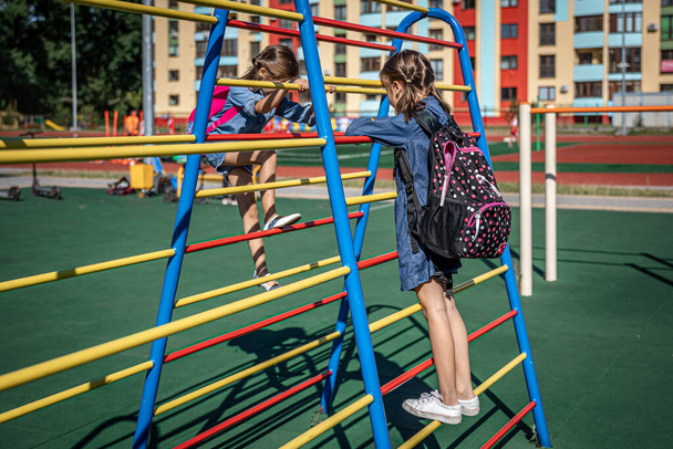 Két kislány, általános iskolás diákok, játszanak a játszótéren iskola után.. - Fotó, kép