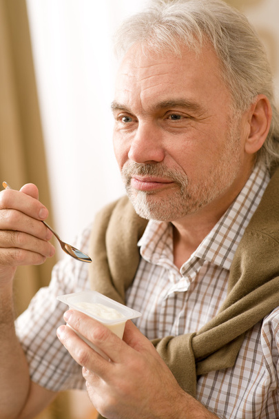 Senior mature man eat yogurt snack - Foto, afbeelding