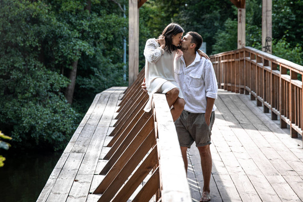 Bella giovane coppia che si bacia su un ponte nella foresta, un appuntamento nella natura, storia d'amore. - Foto, immagini