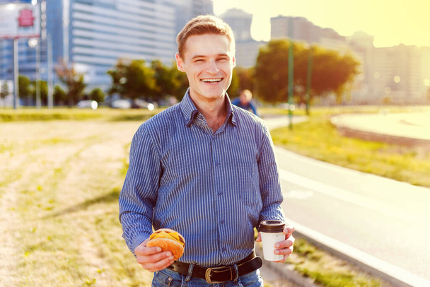 young man with cup of coffee and drinking tea on the street - Photo, Image