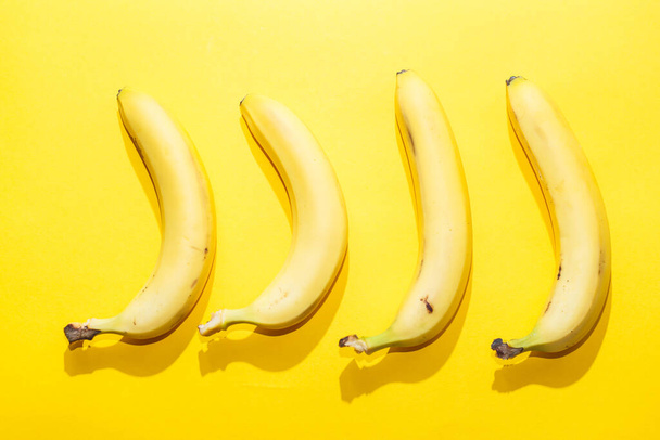 Banany na żółtym pastelowym tle. minimalna koncepcja żywności. - Zdjęcie, obraz