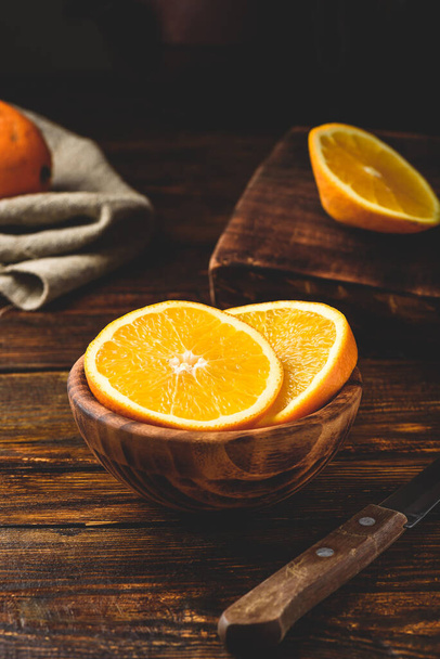 Slices of orange in a rustic wooden bowl - Foto, afbeelding
