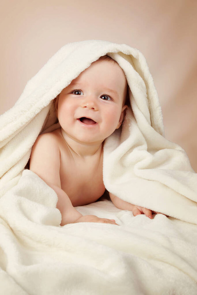 Χαριτωμένο οκτώ μηνών μωρό τυλιγμένο σε μια πετσέτα. Υγιεινή του μωρού. Αξιολάτρευτο μικρό αγόρι - Φωτογραφία, εικόνα