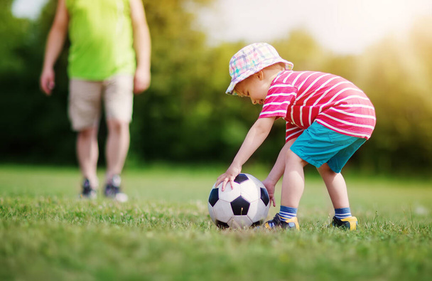 Little boy playting football on the field with gates. Active child in summer with ball - Foto, Bild