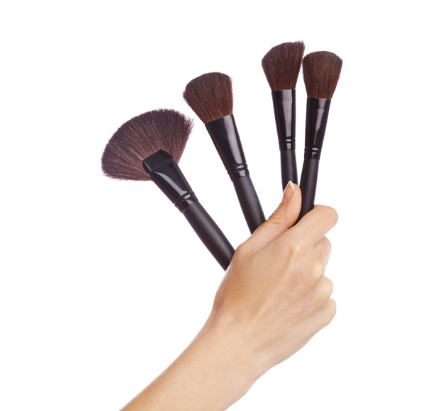 Female hand holding a set of makeup brushes, white background - Zdjęcie, obraz