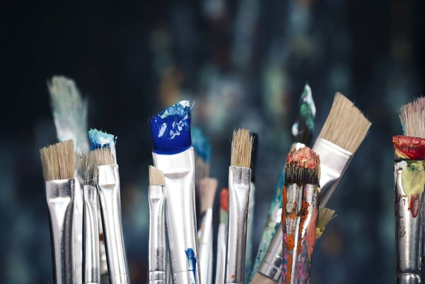 Paint brushes in front of blurred canvas - Foto, Bild
