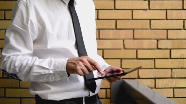Businessman holding digital tablet computer, standing at the office balcony with yellow brick wall. 1920x1080 full hd footage. - Filmmaterial, Video