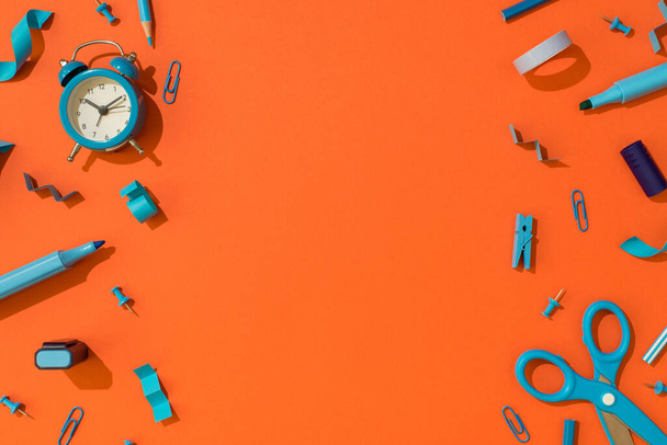 Top view photo of blue school accessories stationery markers pencils adhesive tape clips pushpins scissors and alarm clock on isolated orange background with copyspace - Photo, Image