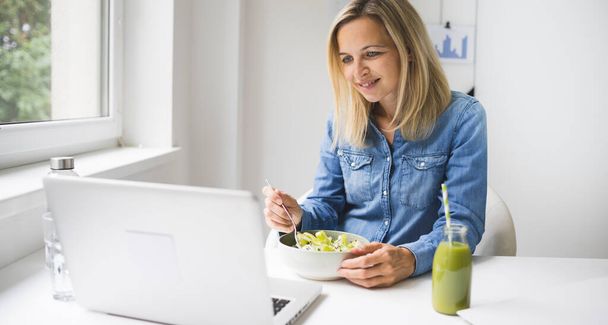 Pretty young business woman eating healthy salad in office - 写真・画像