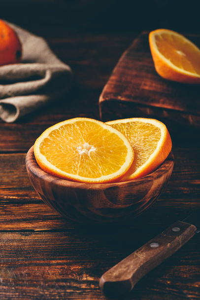 Slices of orange in a rustic wooden bowl - Фото, изображение