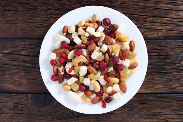 Sekoita pähkinät ja kuivat hedelmät lautasella puupohjalla, ylhäältä - Valokuva, kuva