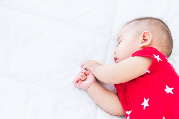 Portrait of beautiful Asian newborn little baby sleeping on white bed at home, Happy baby wears a red shirt relaxing pillow in the room, Family morning at home - Fotoğraf, Görsel