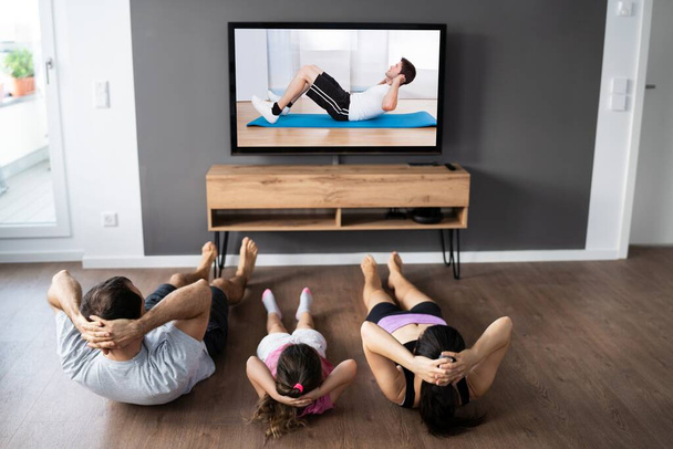 Family Family Doing Fitness Exercise While Watching TV - Фото, зображення