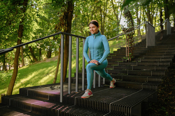 Morning workout on stairs in park, sportive woman. Female runner goes in for sports at sunny day, healthy lifestyle, girl on outdoors training - Фото, зображення