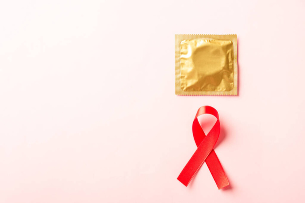 Red bow ribbon symbol HIV, AIDS cancer awareness and condom with shadows, studio shot isolated on pink background, Healthcare medicine sexually concept, World AIDS Day - Foto, immagini