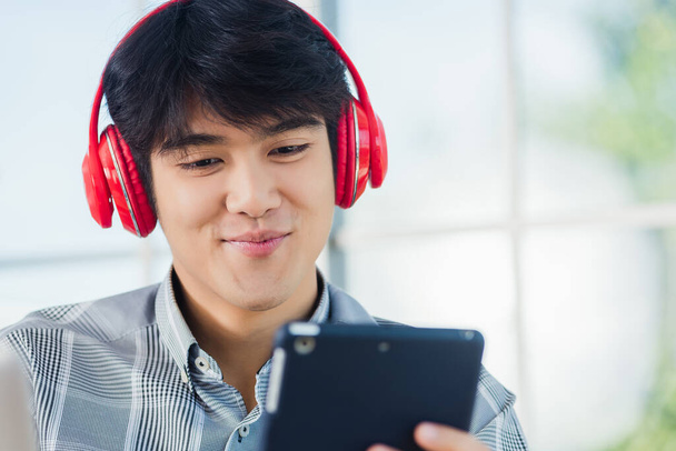 Asian young business man happiness with red headphones he sitting on desk workplace using digital tablet while greeting by video chat conferences talking and discussing - Фото, зображення