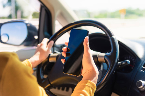 Asian woman inside a car and using a hand holding mobile smartphone blank screen while driving the car in the morning during going to work on highway, Transportation and vehicle concept - Zdjęcie, obraz