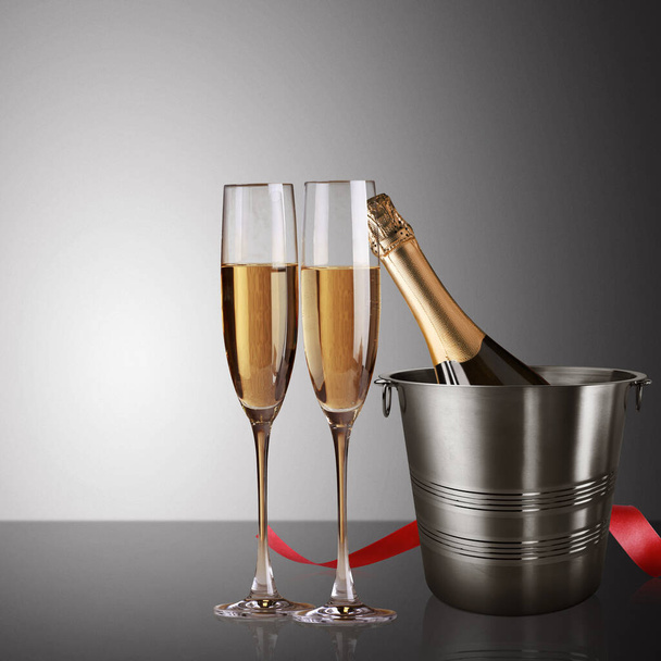 champagne glasses with a glass of wine and a bottle with a bow on a black background - Valokuva, kuva
