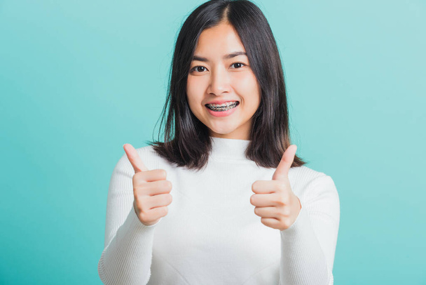 Young beautiful Asian woman cheerful smiling showing finger thumb up, Portrait happy female using showing like the gesture for good sign, studio shot isolated on a blue background - Foto, imagen