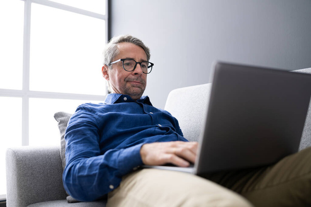 Man Using Laptop Sitting On Couch At Home - Foto, immagini