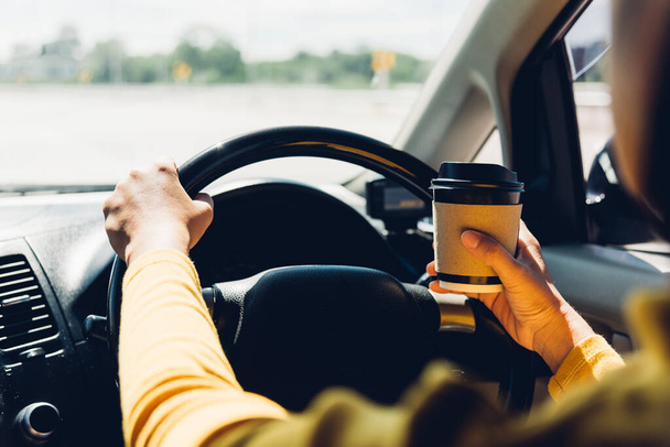 Asian woman drinking hot coffee takeaway cup inside a car and while driving the car in the morning during going to work on highway, Transportation and vehicle concept - Foto, Imagem