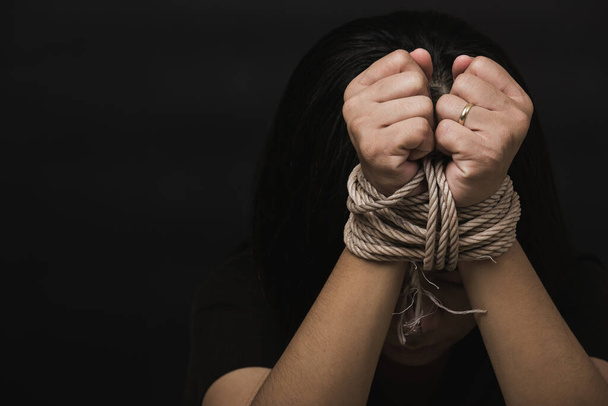 Slave Asian woman fears she was hands tied up with rope black background. Stop violence against kidnap trafficking, International Human Rights day - Φωτογραφία, εικόνα