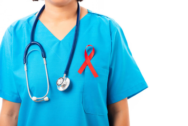 Woman nurse in clinic uniform with support HIV AIDS awareness red ribbon on the chest in studio shot isolated on over white background, Healthcare and medicine, World aids day concept - Photo, Image